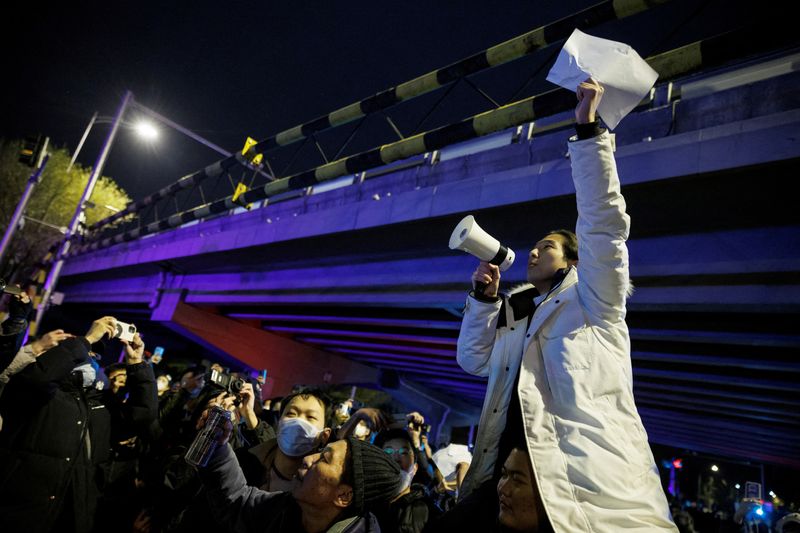 &copy; Reuters. FILE PHOTO: A man holds white sheets of paper in protest over coronavirus disease (COVID-19) restrictions after a vigil for the victims of a fire in Urumqi, as outbreaks of COVID-19 continue, in Beijing, China, November 28, 2022. REUTERS/Thomas Peter