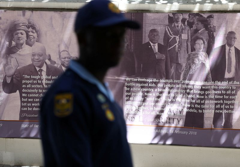 © Reuters. A police official walk past a poster depicting former South African president Jacob Zuma and president Cyril Ramaphosa, following the release of a misconduct report regarding Ramaphosa in Cape Town, South Africa, December 2, 2022. REUTERS/Esa Alexander