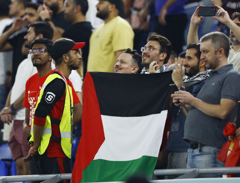 &copy; Reuters. مشجعون يرفعون علما فلسطينيا خلال مباراة صربيا أمام سويسرا بكأس العالم لكرة القدم في الدوحة يوم الجمعة. تصوير: صهيب سالم - رويترز. 
