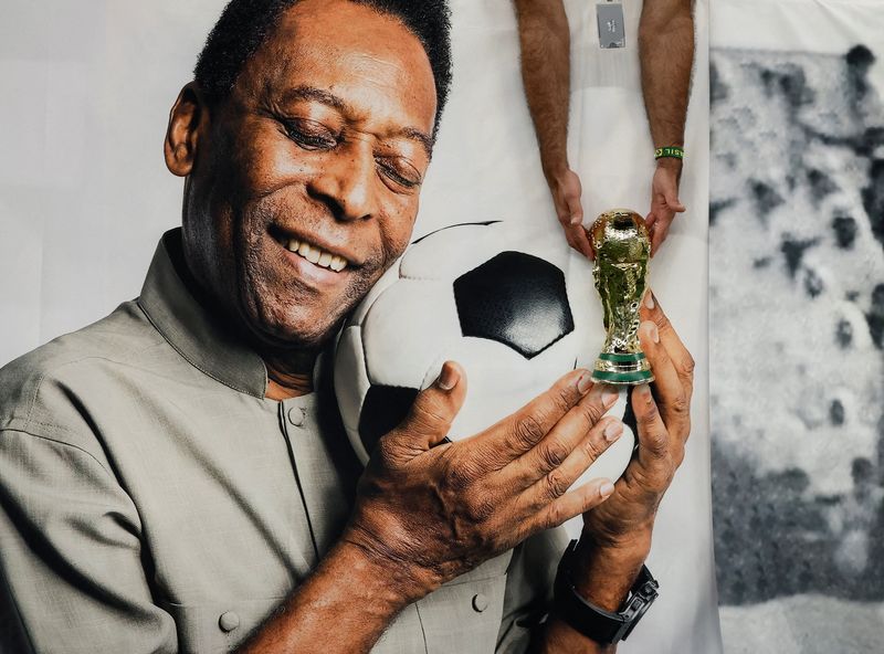 &copy; Reuters. Torcedor brasileiro segura réplica do troféu da Copa do Mundo ao lado de faixa com a foto da lenda do futebol Pelé no Estádio Lusail, antes de partida entre Brasil e Camarões pela Copa do Mundo do Catar
02/12/2022 REUTERS/Benoit Tessier