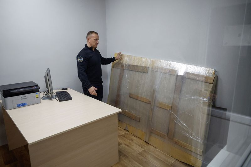 © Reuters. Andrii Nebytov, chief of the Kyiv regional National Police, stands next to the work of street artist Banksy which a group of people tried to steal from a wall of a residential building in the town of Hostomel, heavily damaged during Russian invasion, at a police office in the town of Boiarka, Kyiv region, Ukraine December 3, 2022.  REUTERS/Valentyn Ogirenko