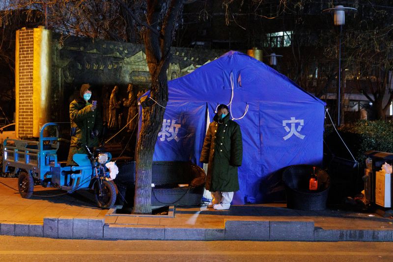&copy; Reuters.  １２月４日、中国では、新型コロナウイルス対策の厳格な行動制限を緩和する動きがさらに広がった。写真は４日、北京の街頭の新型コロナ対策施設前に立つ関係者（２０２２年　ロイタ