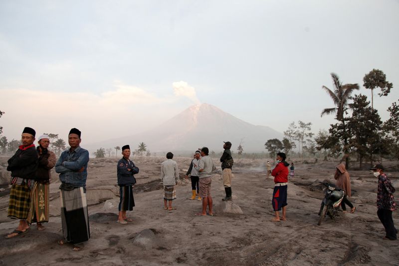 &copy; Reuters. Villagers stand in an area covered with volcanic ash as Mount Semeru volcano erupts volcanic materials, as seen in the background in Sumberwuluh, Lumajang, East Java province, Indonesia, December 5, 2022, in this photo taken by Antara Foto. Antara Foto/Um