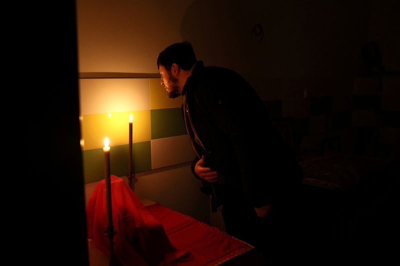 &copy; Reuters. 　ウクライナのゼレンスキー大統領は４日夜の演説で、越冬に向け国民に忍耐と団結を呼びかけた。国内では電力などの復旧作業が続けられている。写真は停電している教会で礼拝後にろう