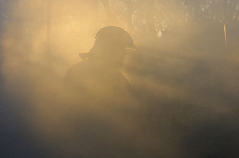© Reuters. A firefighter walks amid smoke while working in an office building heavily damaged in shelling in the course of Russia-Ukraine conflict in Donetsk, Russian-controlled Ukraine, December 5, 2022. REUTERS/Alexander Ermochenko