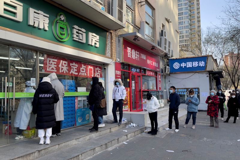 &copy; Reuters. Personas con mascarillas hacen cola frente a una farmacia para comprar productos mientras continúan los brotes de la enfermedad por coronavirus (COVID-19) en Pekín, China, el 6 de diciembre de 2022. REUTERS/Alessandro Diviggiano