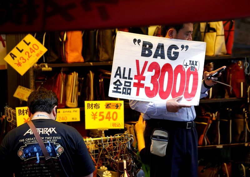 &copy; Reuters. Un employé de magasin tient une pancarte pour attirer les clients à Tokyo. /Photo prise le 16 mai 2018/REUTERS/Issei Kato