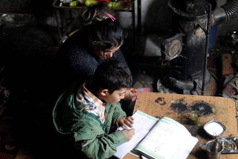 &copy; Reuters. FOTO DE ARCHIVO: Ahlam Mohsin Warda, una madre soltera responsable del cuidado de tres hijos, ayuda a su hijo con sus estudios en su casa en Damasco, Siria, el 30 de noviembre de 2022.  REUTERS/Yamam al Shaar