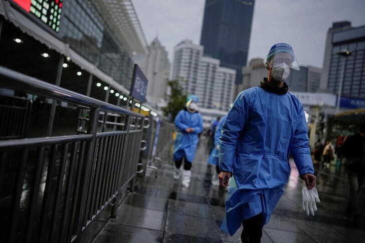 &copy; Reuters. Trabajadores con trajes protectores al exterior de una estación de tren de Shanghái, China. 8 diciembre 2022. REUTERS/Aly Song