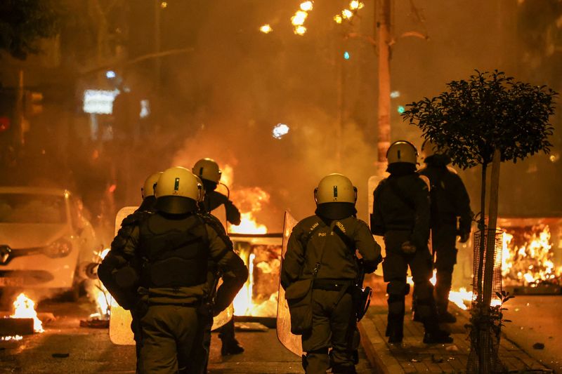 &copy; Reuters. Agenti della polizia antisommossa camminano accanto a barricate in fiamme durante gli scontri con i manifestanti, a seguito di una manifestazione per l'anniversario dell'uccisione, nel 2008, dello studente quindicenne Alexandros Grigoropoulos da parte del