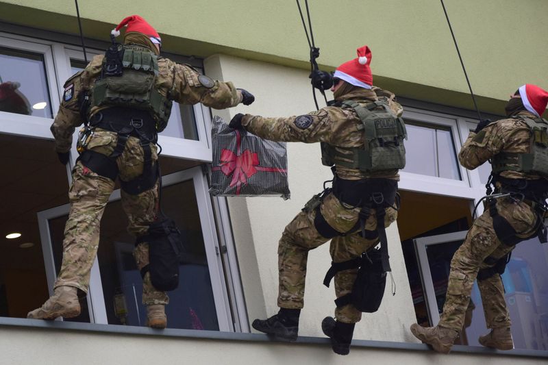 &copy; Reuters. Agentes de la policía antiterrorismo de Polonia cuelgan de las ventanas para entregar regalos a los pacientes de un hospital infantil en el día de San Nicolás, mientras descienden en rappel desde el tejado, en Rzeszów, Polonia. 6 de diciembre, 2022. P