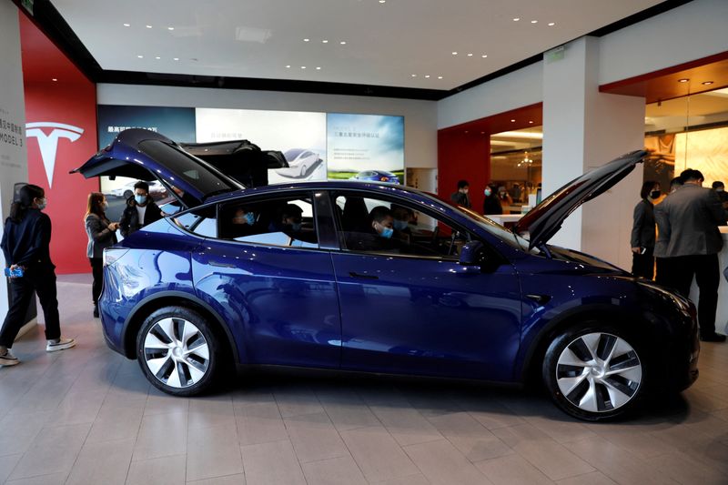 © Reuters. FILE PHOTO: Visitors wearing face masks check a China-made Tesla Model Y sport utility vehicle (SUV) at the electric vehicle maker's showroom in Beijing, China January 5, 2021. REUTERS/Tingshu Wang/File Photo