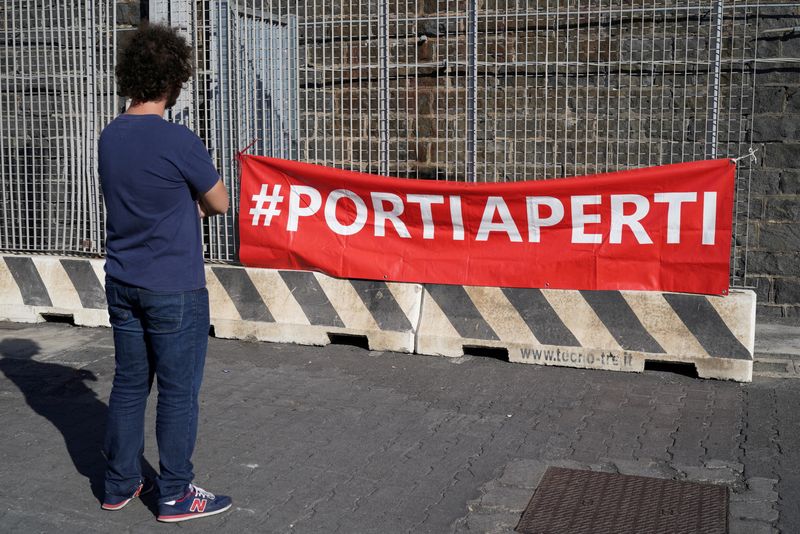 &copy; Reuters. FOTO DE ARCHIVO: Un hombre observa una pancarta en la que se lee "puertos abiertos" en italiano, en demanda de la apertura de los puertos italianos a los barcos de rescate de migrantes, en Catania, Italia, el 7 de noviembre de 2022. REUTERS/Antonio Parrin