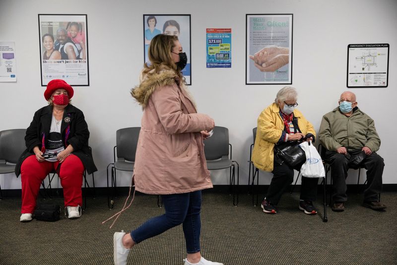&copy; Reuters. People sit in the waiting room as patients are called back to receive their coronavirus disease (COVID-19) vaccine boosters at the North Oakland Health Center in Pontiac, Michigan, U.S., December 21, 2021.  REUTERS/Emily Elconin
