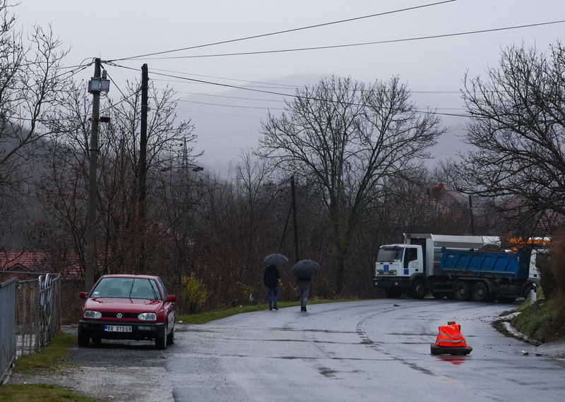 &copy; Reuters. Personas caminan cerca de un bloqueo con camiones en la parte norte de la ciudad étnicamente dividida de Mitrovica, Kosovo, el 11 de diciembre de 2022. REUTERS/Florion Goga