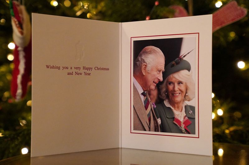 © Reuters. The 2022 Christmas card of Britain's King Charles and Queen Consort Camilla, taken during the Braemar Games September 3, 2022, is displayed in front of a Christmas tree in Clarence House in London, Britain released on December 11, 2022.   Sam Hussein/Buckingham Palace/Handout via REUTERS    