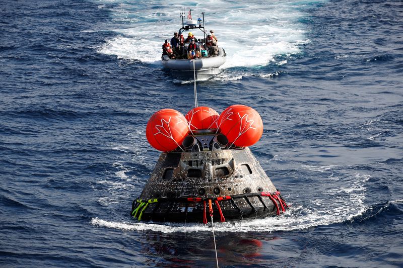© Reuters. U.S. Navy divers attach winch cables to NASA's Orion capsule after being successfully secured by a NASA and U.S. Navy team, off the coast of Baja California, Mexico, 11 December 2022. CAROLINE BREHMAN/Pool via REUTERS