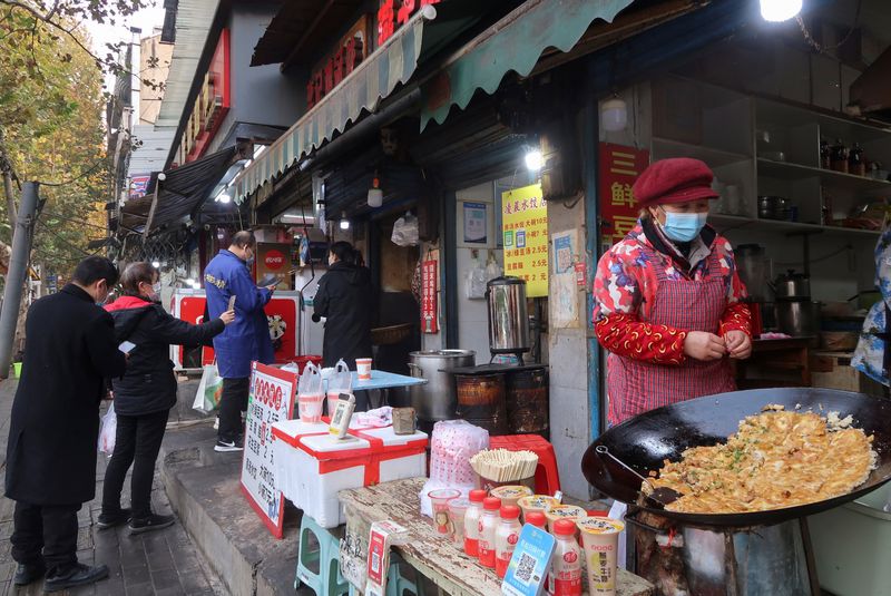 © Reuters. People line up at a food stall in the morning, after the government eased curbs on the coronavirus disease (COVID-19) control, in Wuhan, Hubei province, China December 10, 2022. REUTERS/Martin Pollard