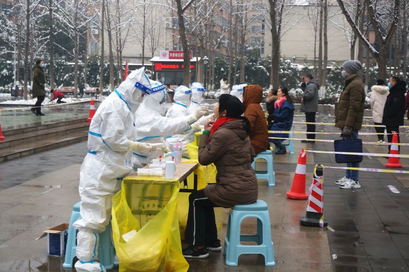 &copy; Reuters. FILE PHOTO: Medical workers in protective suits collect swabs from residents during a citywide nucleic acid testing following cases of the coronavirus disease (COVID-19) in Zhengzhou, Henan province, China, January 5, 2022. cnsphoto via REUTERS   