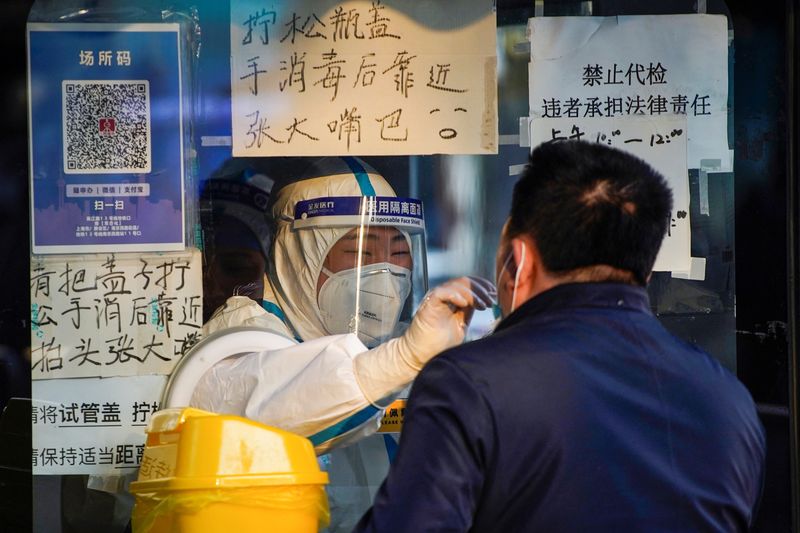 © Reuters. A medical worker in a protective suit collects a swab sample from a man at a nucleic acid testing site, as coronavirus disease (COVID-19) outbreaks continue in Shanghai, China, December 12, 2022. REUTERS/Aly Song