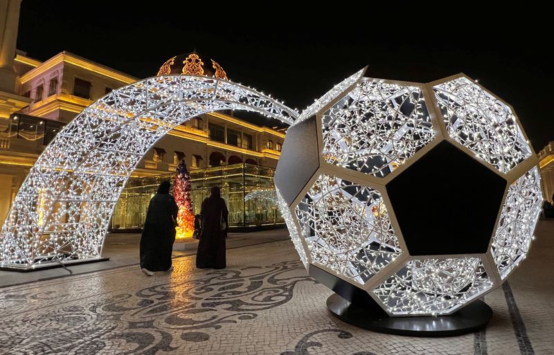 &copy; Reuters. FOTO DE ARCHIVO. Un grupo de personas pasa junto a un balón de fútbol iluminado antes de la Copa Mundial de la FIFA 2022 en la Aldea Cultural de Katara en Doha, Qatar. 15 de noviembre de 2022. REUTERS/Fabrizio Bensch