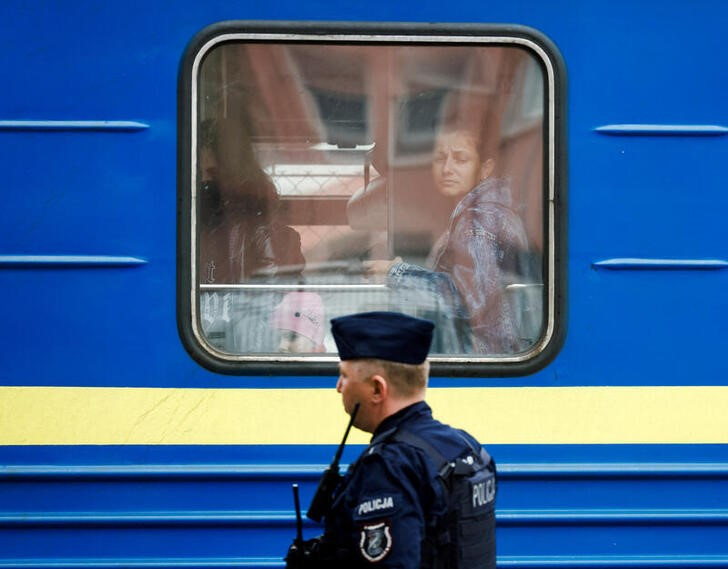 &copy; Reuters. Imagen de archivo de refugiados ucranianos mirando por la ventana de un tren procedente de Odesa mientras un policía hace guardia en la estación de tren de Przemysl Glowny, en Przemysl, Polonia. 21 abril 2022. REUTERS/Darrin Zammit Lupi