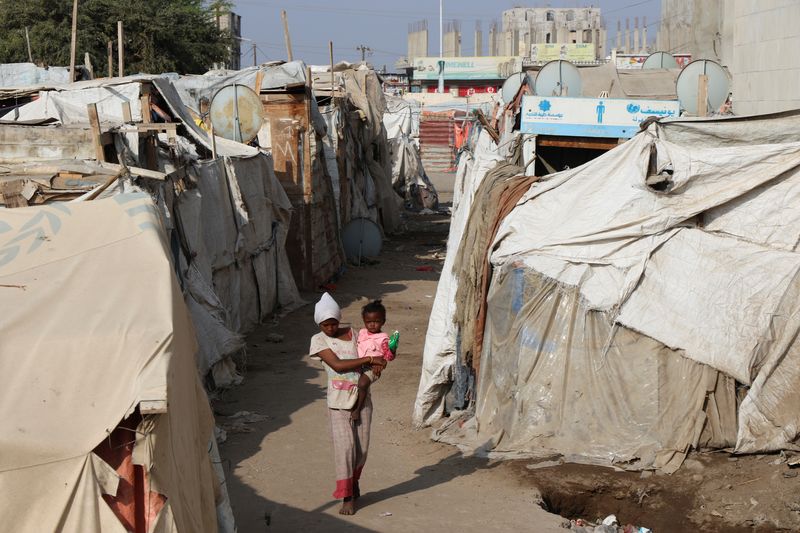 &copy; Reuters. Une fille porte un enfant alors qu'elle marche dans un camp de fortune pour personnes déplacées à Aden, au Yemen. /Photo prise le 15 mars 2022/REUTERS/Fawaz Salman
