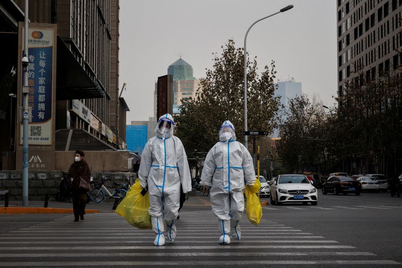 &copy; Reuters. FOTO DE ARCHIVO. Trabajadores de prevención con trajes protectores cruzan una calle mientras continúan los brotes de la enfermedad por coronavirus (COVID-19) en Pekín, China. 9 de diciembre de 2022. REUTERS/Thomas Peter
