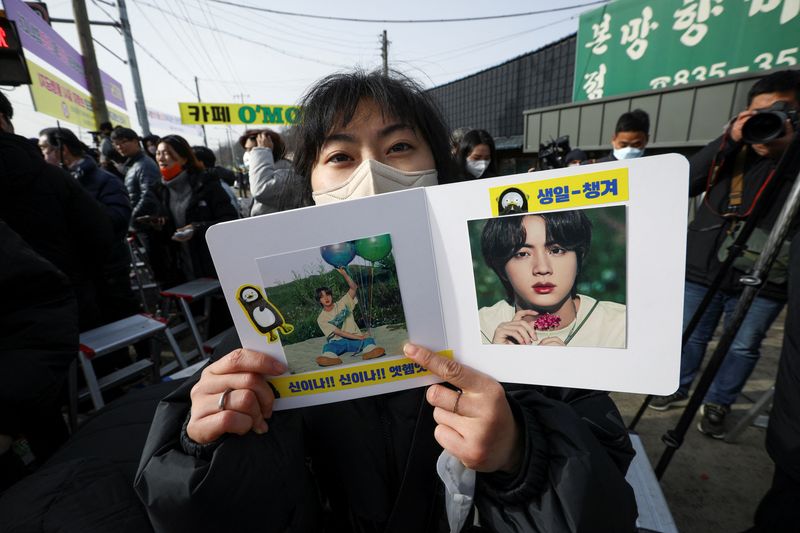 &copy; Reuters. معجبة تحمل صورة جين عضو فرقة البوب الشهيرة بي.تي.إس خارج معسكر تدريب للجيش الكوري الجنوبي في يونتشون يوم الثلاثاء. تصوير: هيو ران-رويترز.
