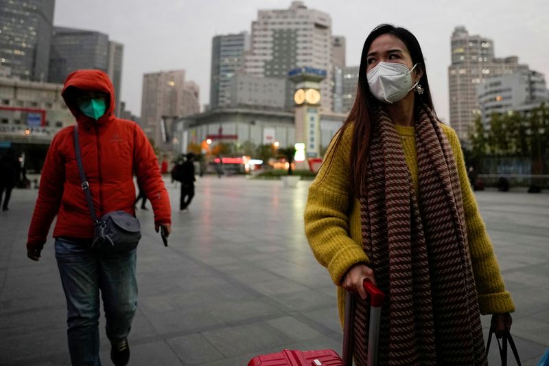 &copy; Reuters. Personas con máscaras protectoras caminan fuera de la estación de tren de Shanghái, mientras continúan los brotes de la enfermedad por coronavirus (COVID-19) en Shanghái, China. 13 de diciembre de 2022. REUTERS/Aly Song