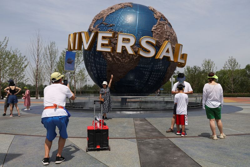 &copy; Reuters. FILE PHOTO: A tourist poses in front of a sign of the Universal Resort, as the Universal Studios theme park reopens to the general public, following the coronavirus disease (COVID-19) outbreak in Beijing, China June 25, 2022. REUTERS/Tingshu Wang