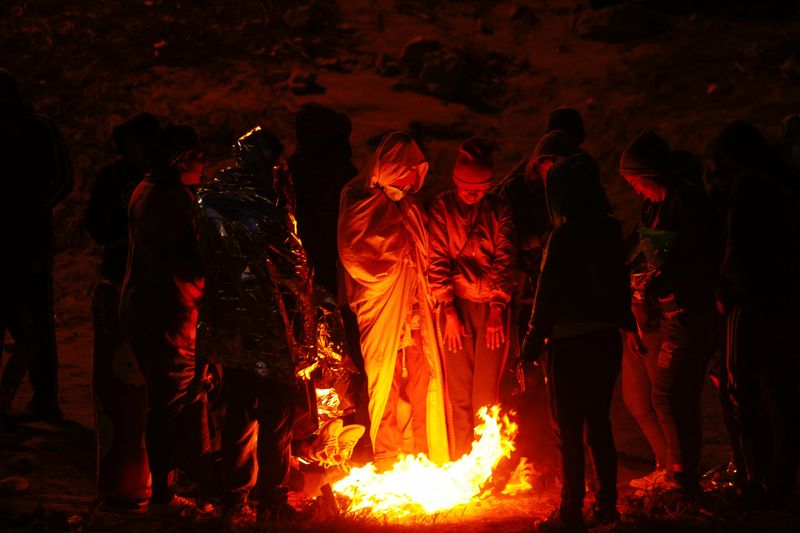 © Reuters. Migrants build a bonfire near the border wall after crossing the Rio Bravo river to turn themselves in to U.S. Border Patrol agents to request asylum in El Paso, Texas, U.S., as seen from Ciudad Juarez, Mexico December 13, 2022. REUTERS/Jose Luis Gonzalez