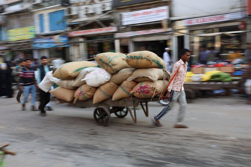 &copy; Reuters. Workers transport sacks that are loaded on a cart at a wholesale market in the old quarters of Delhi, India, December 7, 2022. REUTERS/Anushree Fadnavis/Files