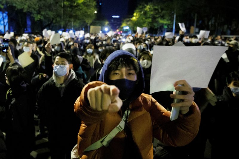 &copy; Reuters. Photo d'archives : Des personnes tiennent des feuilles de papier blanc en signe de protestation contre les restrictions liées au coronavirus (COVID-19), après une veillée pour les victimes d'un incendie à Urumqi, alors que les épidémies de COVID-19 