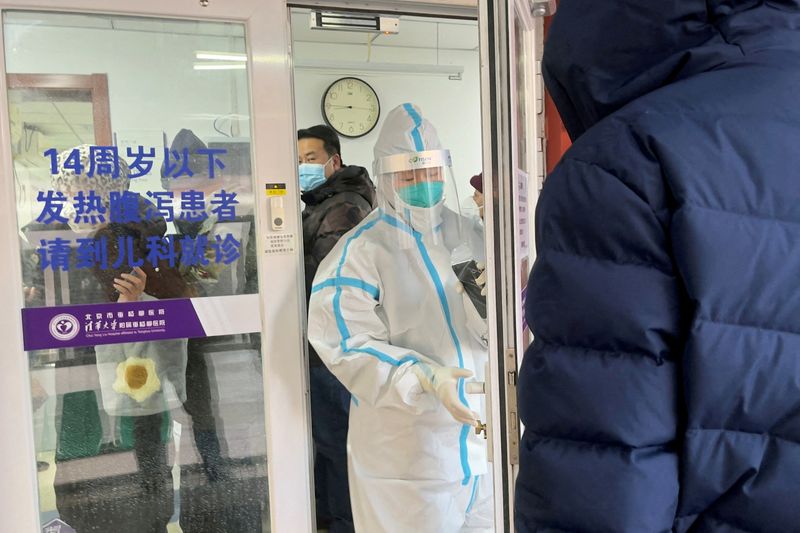 &copy; Reuters. People line up next to a medical worker in a protective suit, at a fever clinic of a hospital amid the coronavirus disease (COVID-19) outbreak in Beijing, China December 15, 2022. REUTERS/Josh Arslan