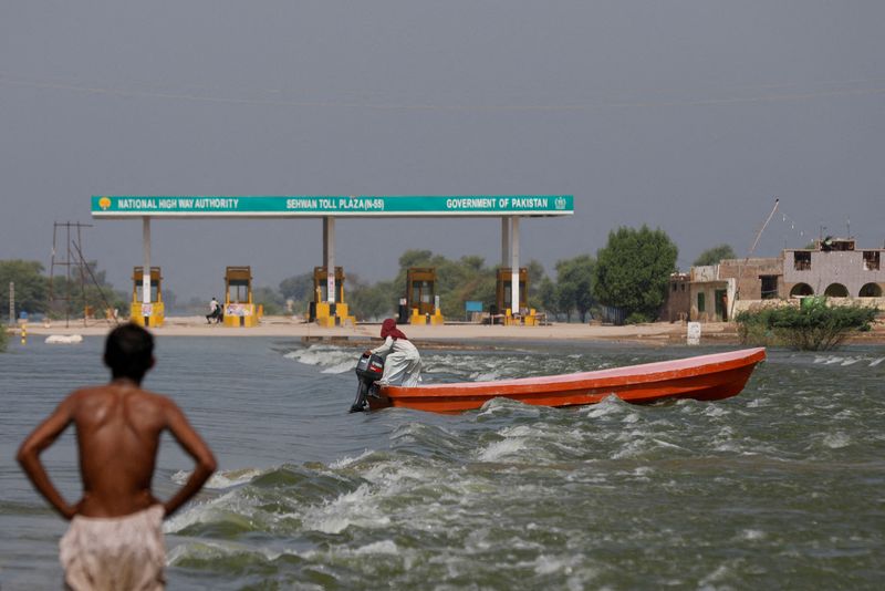 &copy; Reuters. FILE PHOTO: A man rides a boat past toll plaza amid flood water on main Indus highway, following rains and floods during the monsoon season in Sehwan, Pakistan, September 15, 2022. REUTERS/Akhtar Soomro