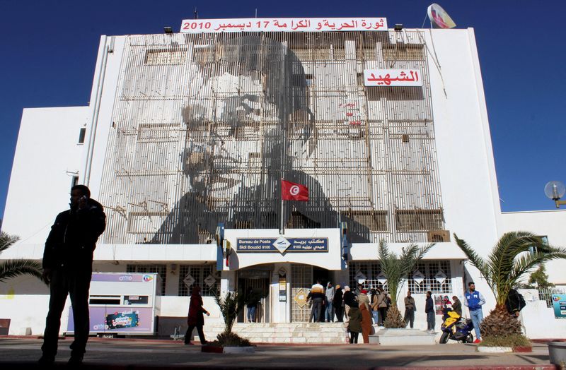 &copy; Reuters. FILE PHOTO: A picture of Mohamed Bouazizi, a street vendor who set himself alight 10 years ago on December 17, 2010, is displayed on the post office building in Sidi Bouzid, Tunisia December 8, 2020. REUTERS/Angus McDowall