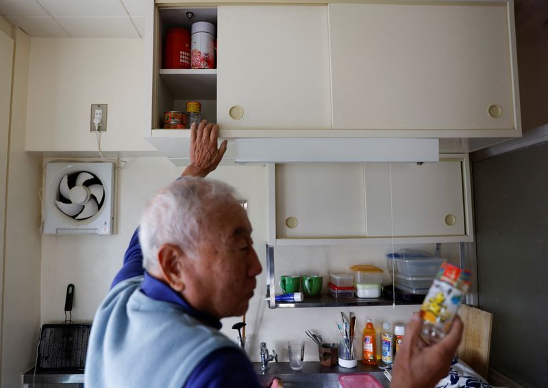 © Reuters. Pensioner Yoshio Koitabashi, 84, shows the contents of his small kitchen cabinet at his apartment in a public housing complex in Tokyo, Japan November 14, 2022.  REUTERS/Issei Kato