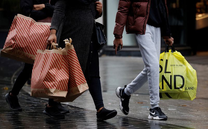 © Reuters. FILE PHOTO: People carry shopping bags as shoppers look for bargains in the traditional Boxing Day sales in Liverpool, Britain, December 26 , 2021. REUTERS/Phil Noble