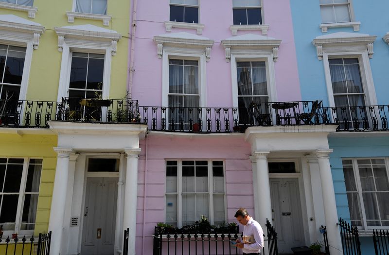 &copy; Reuters. FILE PHOTO: A man walks past houses painted in various colours in a residential street in London, Britain, May 15, 2019. REUTERS/Toby Melville