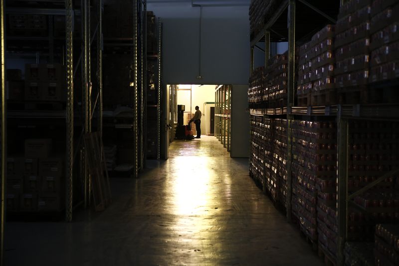 &copy; Reuters. FILE PHOTO: A worker is silhouetted handling a cart inside a warehouse of Vanos marine supply company at Kaminia suburb in Piraeus, near Athens April 2, 2014. REUTERS/Yorgos Karahalis 