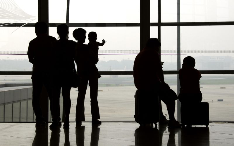 &copy; Reuters. FILE PHOTO: People watch planes on the runway as others sit with their luggage in the terminal three building of the Beijing Capital International Airport July 11, 2011. REUTERS/David Gray 