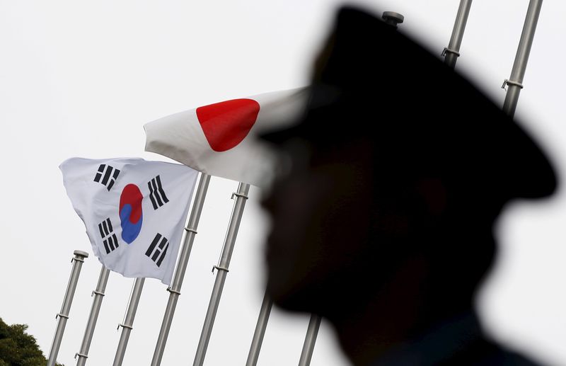 © Reuters. FILE PHOTO: A police officer stands guard near Japan and South Korea national flags at hotel, where South Korean embassy in Japan is holding the reception to mark the 50th anniversary of normalisation of ties between Seoul and Tokyo, in Tokyo  June 22, 2015. East Asian neighbours South Korea and Japan marked the 50th anniversary of diplomatic ties on Monday with a push to mend relations strained for years by a territorial dispute and a feud over Japan's wartime past.   REUTERS/Toru Hanai