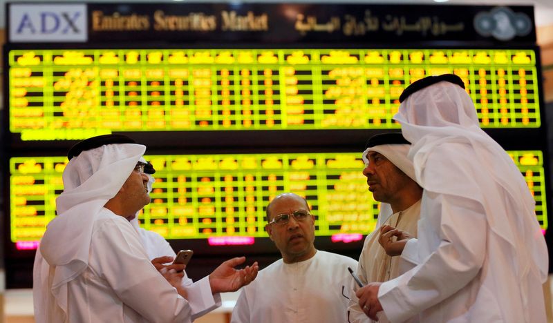 &copy; Reuters. مستثمرون يقفون أمام شاشة تعرض بيانات عن الأسهم في بورصة أبوظبي - صورة من أرشيف رويترز.