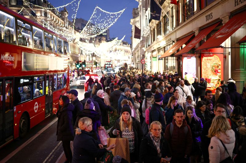 &copy; Reuters. FILE PHOTO: People carry shopping bags as they walk past Christmas themed shop displays on Regent Street in London, December 4, 2022. REUTERS/Henry Nicholls     