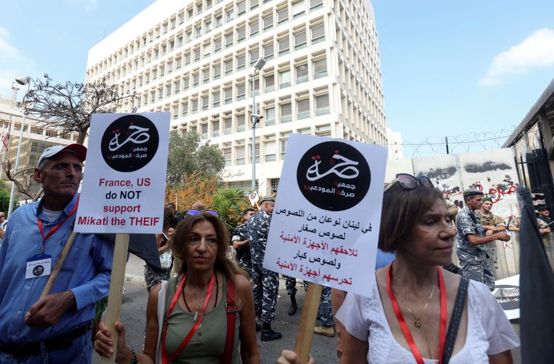 © Reuters. FILE PHOTO: Demonstrators carry banners during a protest organized by Depositors' Outcry, a group campaigning for angry depositors, near Lebanon's Central Bank building in Beirut, Lebanon October 5, 2022. REUTERS/Aziz Taher/File Photo