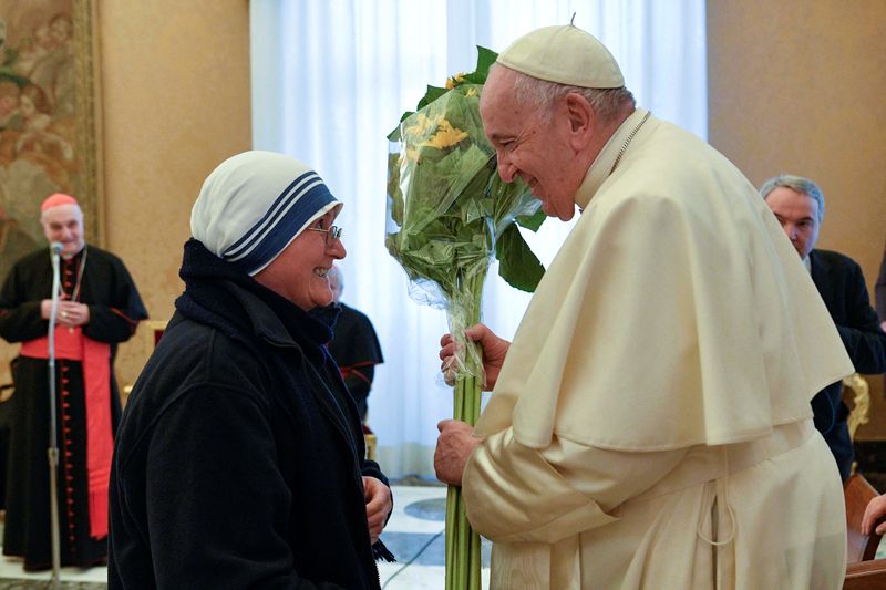 © Reuters.  １２月１７日、 ローマ教皇フランシスコ（写真右）が、８６歳の誕生日を迎え、奉仕活動を行っている３人の人物を、マザー・テレサ賞として顕彰した。写真はバチカンで同日、同賞の関係者から花を受け取る教皇。バチカン提供（２０２２年　ロイター）