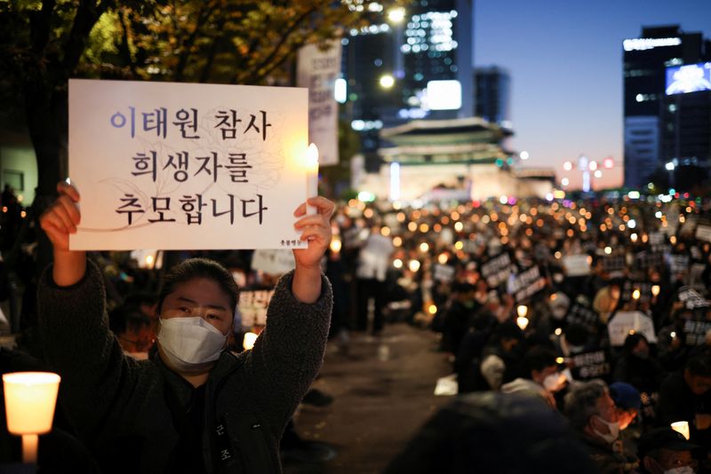 &copy; Reuters. A woman holds a placard during a candlelight vigil to commemorate the victims of the crowd crush that happened during Halloween festivities, at Seoul City Hall Plaza, in Seoul, South Korea, November 5, 2022. The placard reads: "We are commemorating the vi