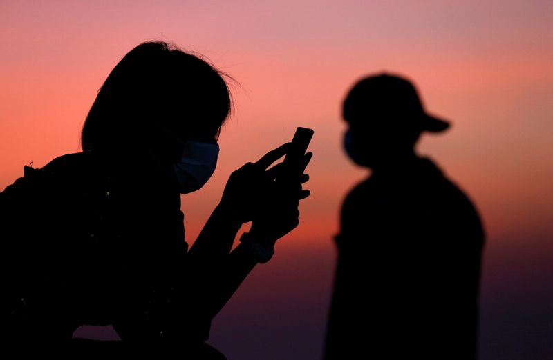 &copy; Reuters. FOTO DE ARCHIVO: Imagen ilustrativa de una persona usando mascarilla mientras mira su teléfono móvil en Pattaya, Tailandia. 27 de marzo, 2020. REUTERS/Soe Zeya Tun/Archivo