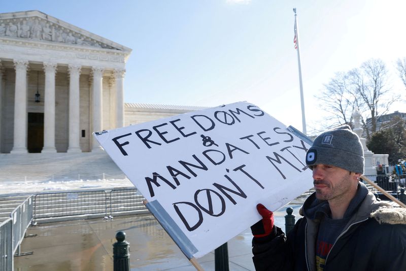 © Reuters. FILE PHOTO: A lone protester stands outside the U.S. Supreme Court as it hears arguments against the Biden administration's nationwide vaccine-or-testing COVID-19 mandates, in Washington, U.S., January 7, 2022.  REUTERS/Jonathan Ernst